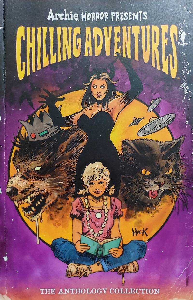 Couverture du comic-book Archie Horror Presents Chilling Adventures. On y voit une femme aux cheveux noirs et en robe noire avec les bras levés. De chaque coté d'elle une tête de loup et une tête de chat et assise devant elle, une petit fille blonde en jeans et en top rose.