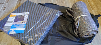 photo de matériel de bricolage comprenant un sac noir posé à plat, un cylindre de tissu recyclé et de la mousse anti-choc sous plastique.